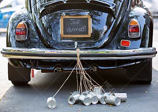 Rear view of a vintage car with just married sign and cans attached