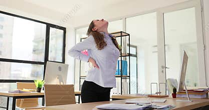 Young stressed businesswoman and with pained expression holding waist in office