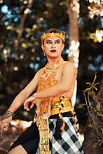 Balinese dancer performs the dance in golden costume and golden crown inside the temple