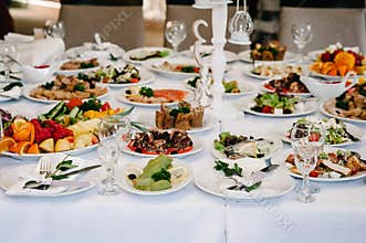 Serves dinner on a festive table. Food, Salads, Meat, Fish Meals. Festive table at wedding banquet. Decor. Details