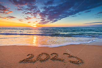 Happy New Year 2023 concept, lettering on the beach. Written text on the sea beach at sunrise