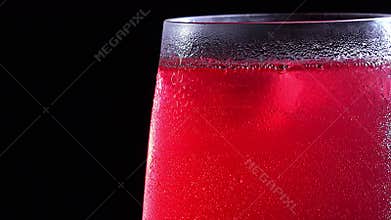 A misted glass with a drink and bubbles in close-up. Cold drink with ice