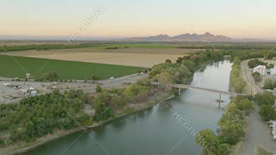 Raising drone shot over the river and large green landscape and trees in Colusa, CA at sunset