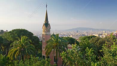 Green palms and flora in Park Guell. City of Barcelona, Spain is seen in the background