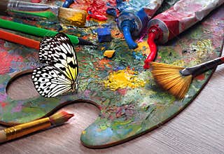 colors of rainbow. colorful tropical morpho butterfly on artist\'s palette with brushes, tubes and strokes of paint.