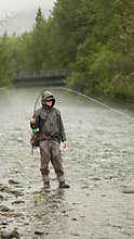 man fly fishing in river fighting fish in river alaska