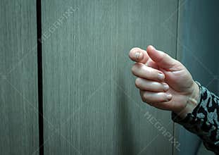Close-up Knocking on the door of an elderly woman, a woman\'s hand knocks on a wooden door, a visit