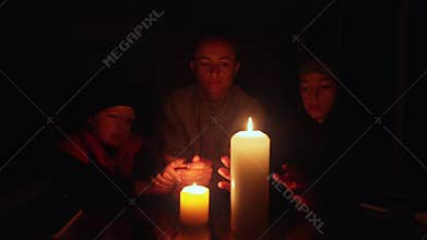 Family sitting around a table lit by candlelight during an electrical power cut