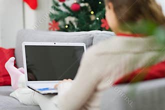 Woman using laptop near Christmas tree. Rear view