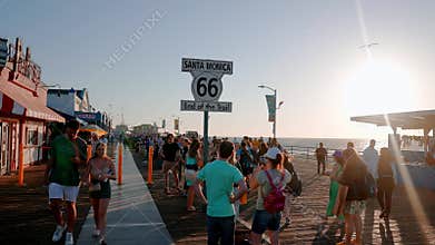 Ferris wheel and roller coaster rides and people exploring shops at the Pacific amusement park