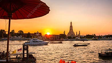 4K Timelapse view of Wat Arun of Bangkok Thailand during sunset with busy boat moving in the river