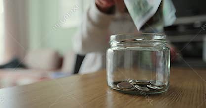 Close up woman and man takes dollars from the piggy bank. Glass jar with cash. The cash in the piggy bank. Family saving