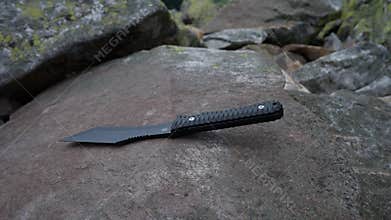 A hunting knife lies on a stone.