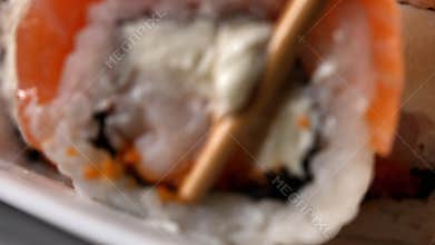 A whole piece of sushi roll against the backdrop of fallen apart ones.