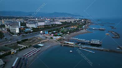Stunning aerial sunset to night transition over Turkler in Alanya, Turkey. Alanya coastline,resorts,marina,hotels and city lights