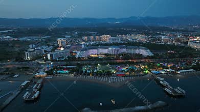 Stunning aerial sunset to night transition over Turkler in Alanya, Turkey. Alanya coastline,resorts,marina,hotels and city lights