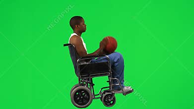 Ethnic boy on a wheelchair playing with a basket ball