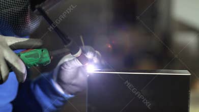 Hands of worker welding in factory