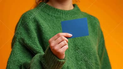 Person holding and rotating blue card against vibrant orange background