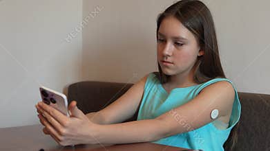 Girl with diabetes checking blood glucose level at home using continuous glucose monitor. girl checks the glucose level