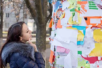 Pensive woman reading advertisements on a board