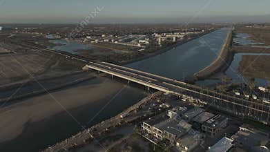 Drone shot of the cars driving on the Pacific Coast Highway crossing Santa Ana River at sunset, USA
