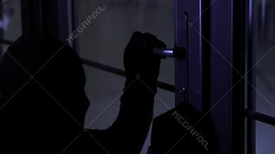 theft, male criminal in balaclava with master key in hands opens door lock, close-up