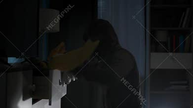 man in hood and balaclava rummages through other people things looking for valuables, runs away when he sees police