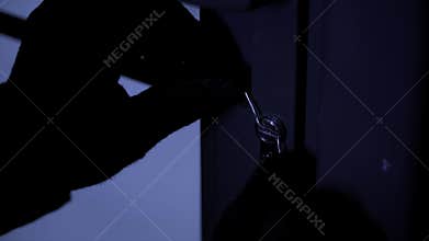 dangerous criminal tries to pick a door lock with master keys, close-up