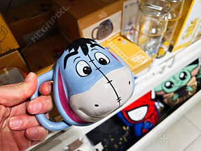 Kyiv, Ukraine - February 05, 2025: Colorful coffee mug with character design held in a retail store display