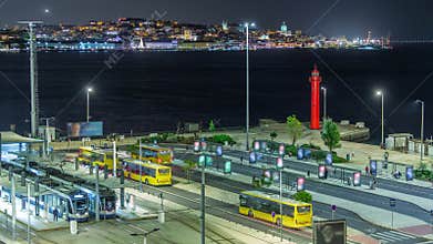 Aerial night timelapse of Cacilhas bus and railway station with the Tagus River, Lisbon glowing skyline