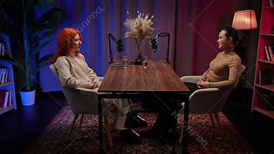 Two Influencers of women being interviewed in a loft-style podcast studio