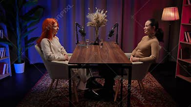 Two Influencers of women being interviewed in a loft-style podcast studio