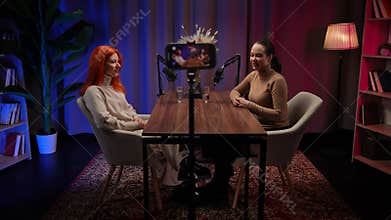 Two Influencers of women being interviewed in a loft-style podcast studio