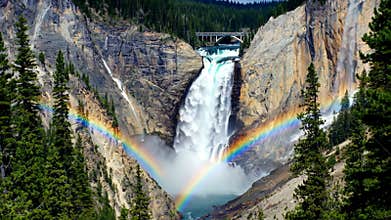 Spectacular waterfall cascading down a rocky canyon with a vibrant rainbow, nature landscape