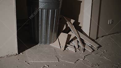 Construction debris scattering around metal trash bin during residential renovation, highlighting messy workspace aftermath