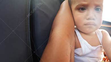 Little boy with brown eyes sits in car seat looking around
