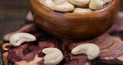 large cashew nuts are scattered on a larch board