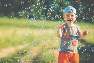 Joyful child playing with bubbles in sunlit park