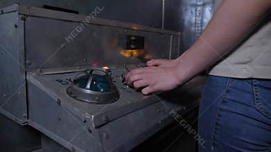 A woman presses buttons on an old control panel in a subway car, quest.