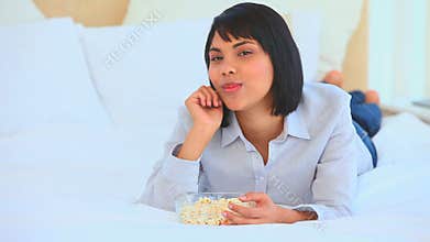 Asian woman on the phone eating popcorn