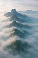 Majestic mountain peaks emerge through a soft blanket of foggy clouds at sunrise
