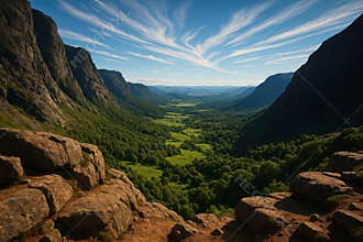 Majestic mountain valley vista under a striking sky with wispy clouds and lush greenery below