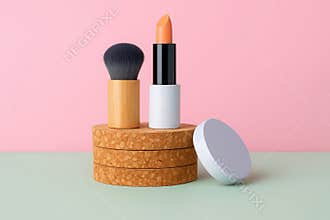 A collection of makeup essentials including a lipstick brush and compact arranged artistically on a textured surface