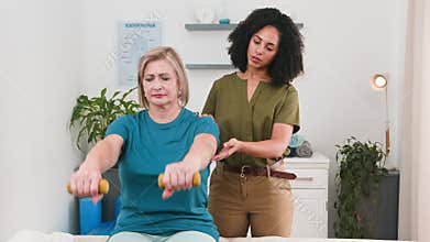 Black Woman Physiotherapist Guides Senior Patient Through Arm Exercises for Rehabilitation and Strength Building