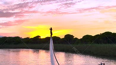 Aerial View 4K: Courageous Woman Flyboarding Over River at Dusk