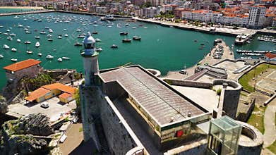 Drone flying on Santa Ana Castle-Lighthouse towards the port of Castro Urdiales with anchored boats