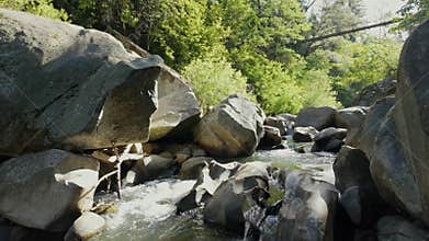 Deer creek rapids over large boulders with a hiking bridge
