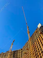 Construction site with a building under construction, dominated by a large yellow crane Exposed steel beams and rebar