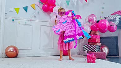 Child girl enjoys a vibrant b-day party, hold and swing pinata
